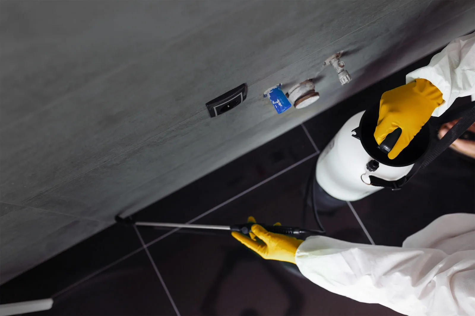 A person in white gloves spraying water on the floor.