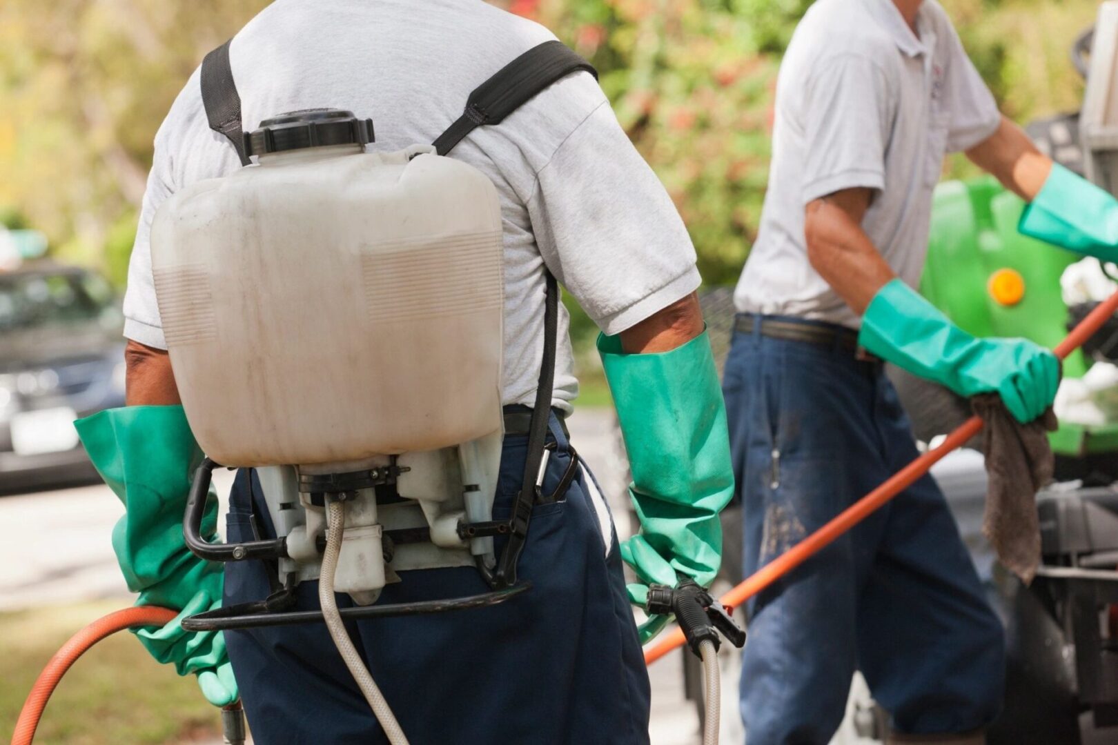 Two men in green gloves and a backpack.