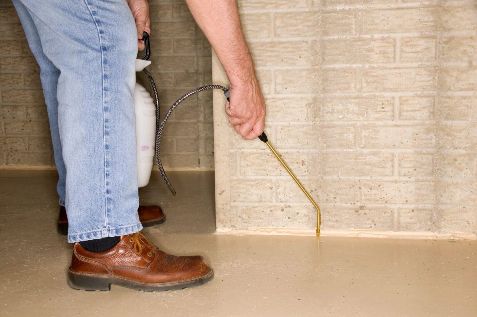 A man is holding a hose and spraying water on the floor.